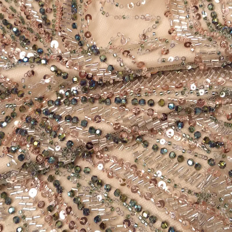 Κοντινό πλάνο του Τούλι κεντημένο 24061 ύφασμα καλυμμένο με περίπλοκες χάντρες και πούλιες σε ροζ, ασημένιο και πράσινο χρώμα, που σχηματίζουν κυματιστά, διακοσμητικά μοτίβα. Υφάσματα Ιχτιάρογλου